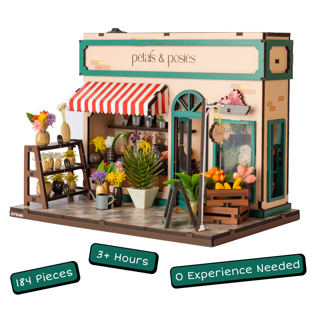 Model of a flower shop with 'petals & posies' sign, surrounded by flowers and plants.